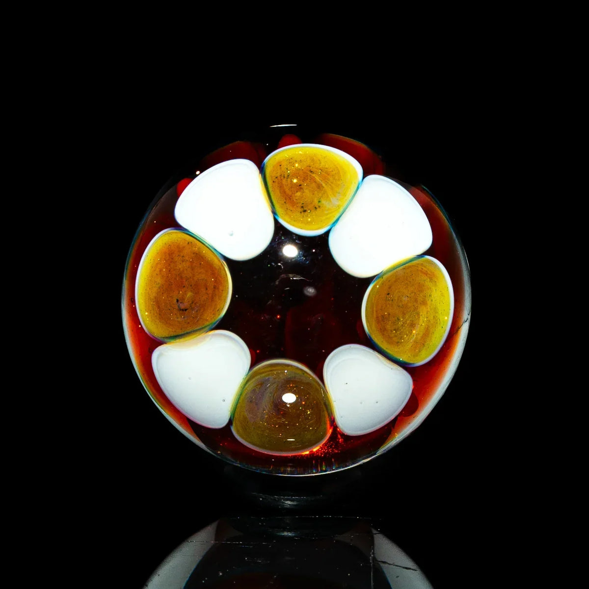 Heady glass marble with red, white, and gold decorative elements on a black background