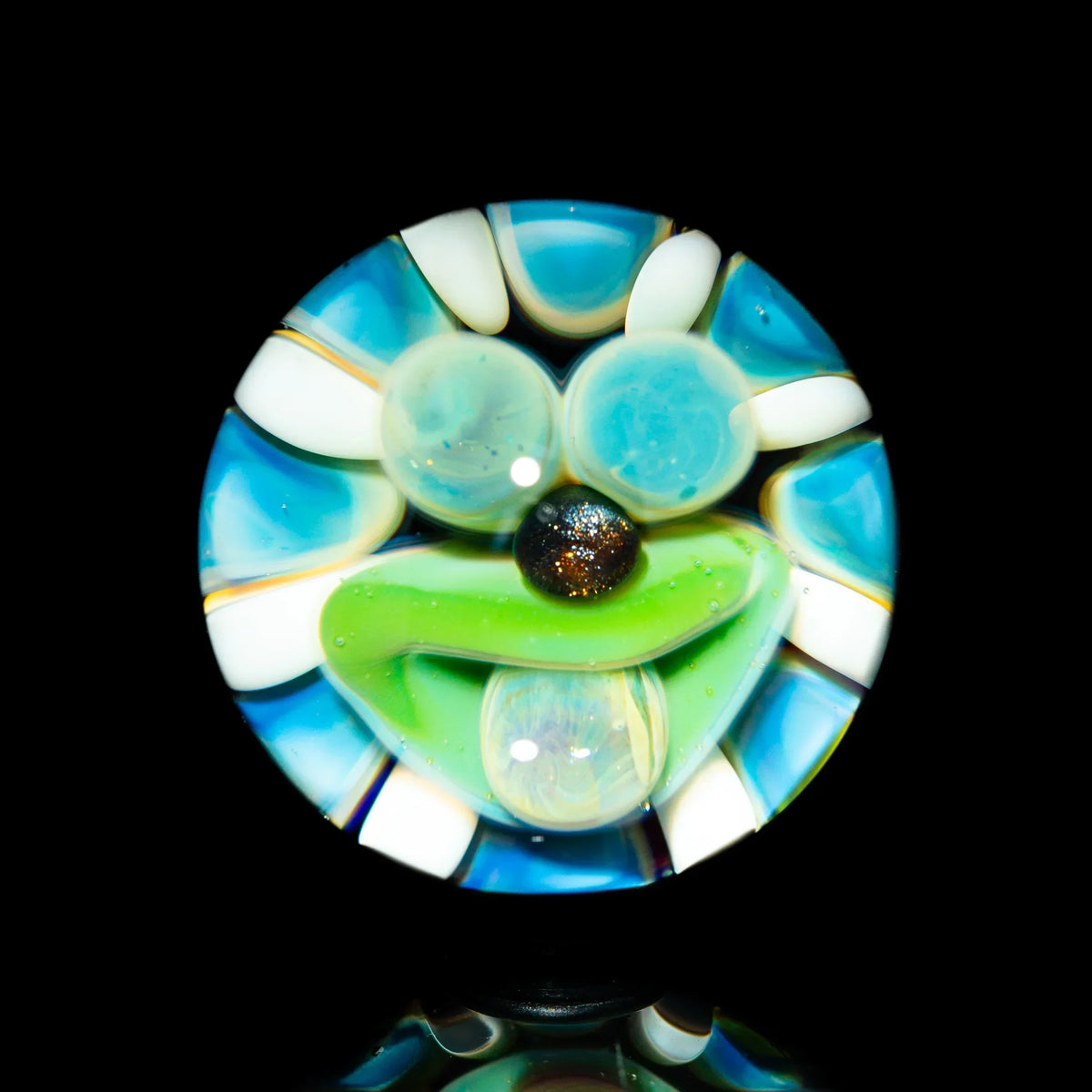 Colorful glass pendant with abstract face design, blue, white, green accents on black background