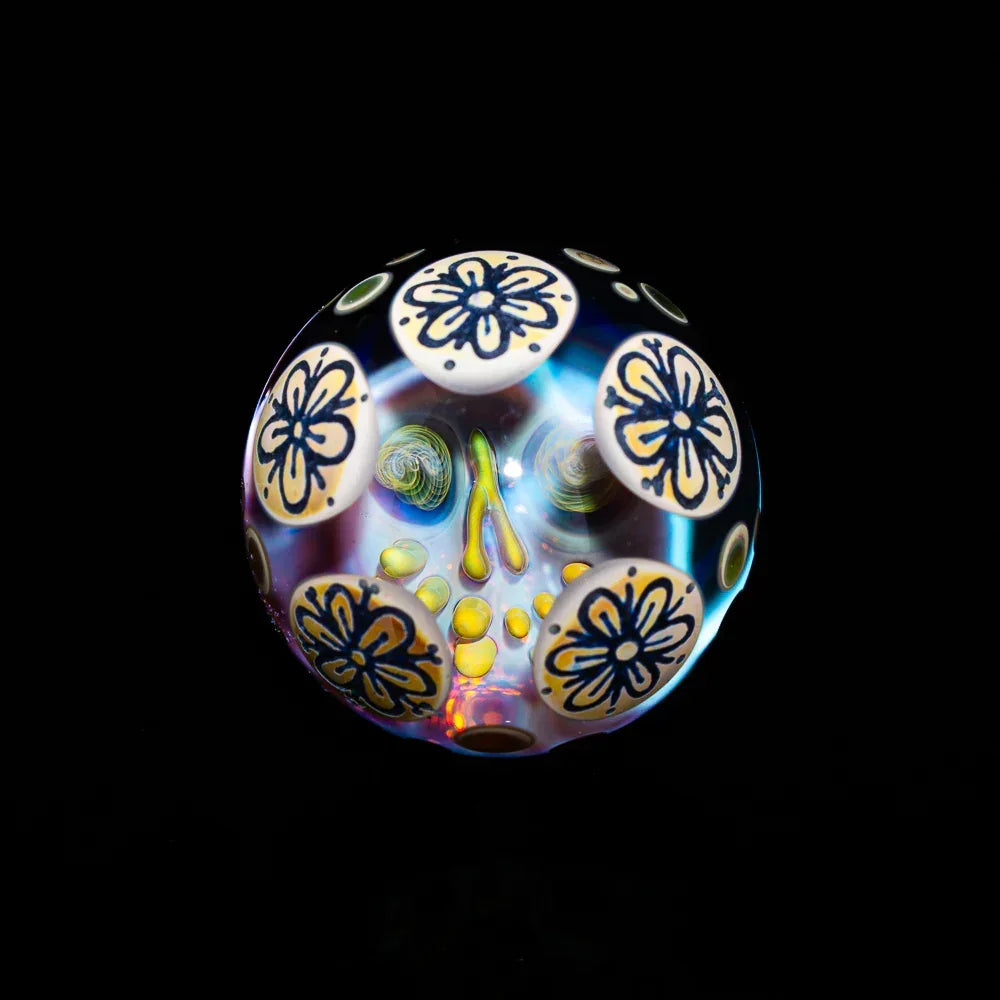 Handcrafted glass marble with intricate floral patterns and bright colors on black background