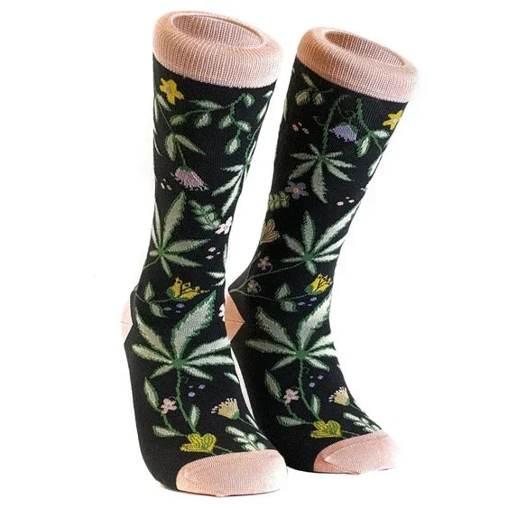 Black crew socks with green leaf and yellow flower pattern, pink heel and cuff accents