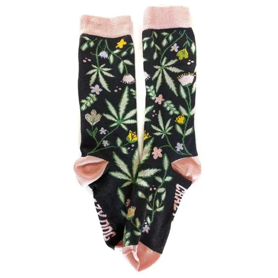 Black socks with pink accents featuring green leaf and floral pattern, novelty cannabis design
