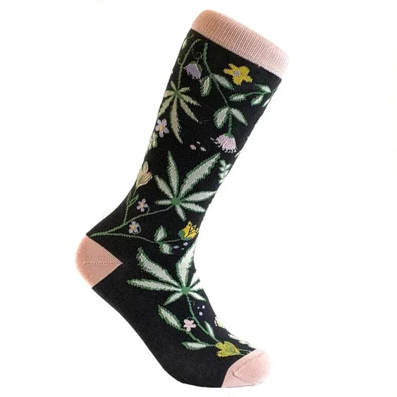 Black crew sock with pink cuff, heel, and toe, featuring green leaf and floral pattern.