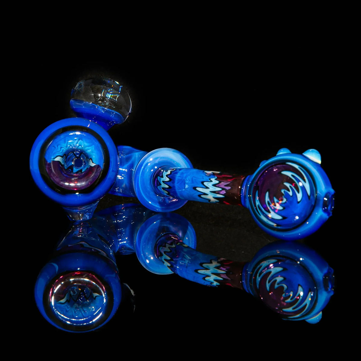 Artistic blue glass hand pipe with colorful marbled accents on a black reflective surface