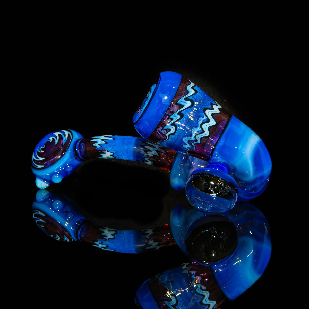Heady glass hand pipe with vibrant blue, purple, and zigzag designs on black background