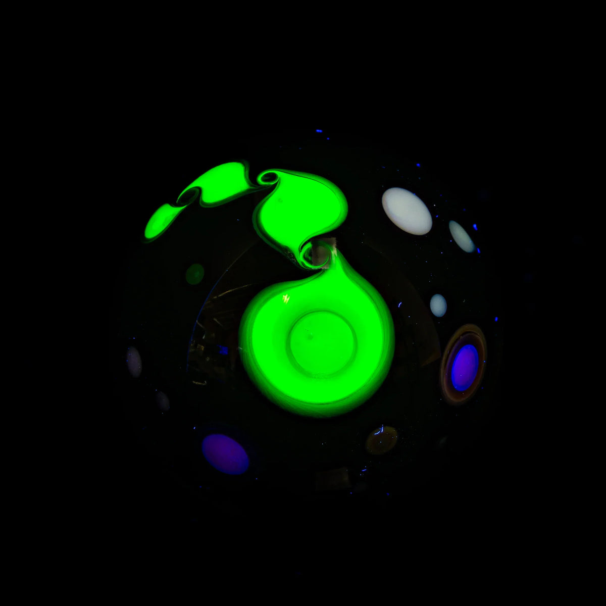 Glowing glass marble with neon green swirl and colorful dot accents on black background