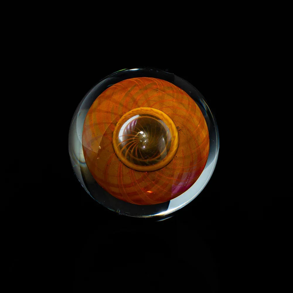 Handcrafted glass marble with orange swirling pattern on a black background