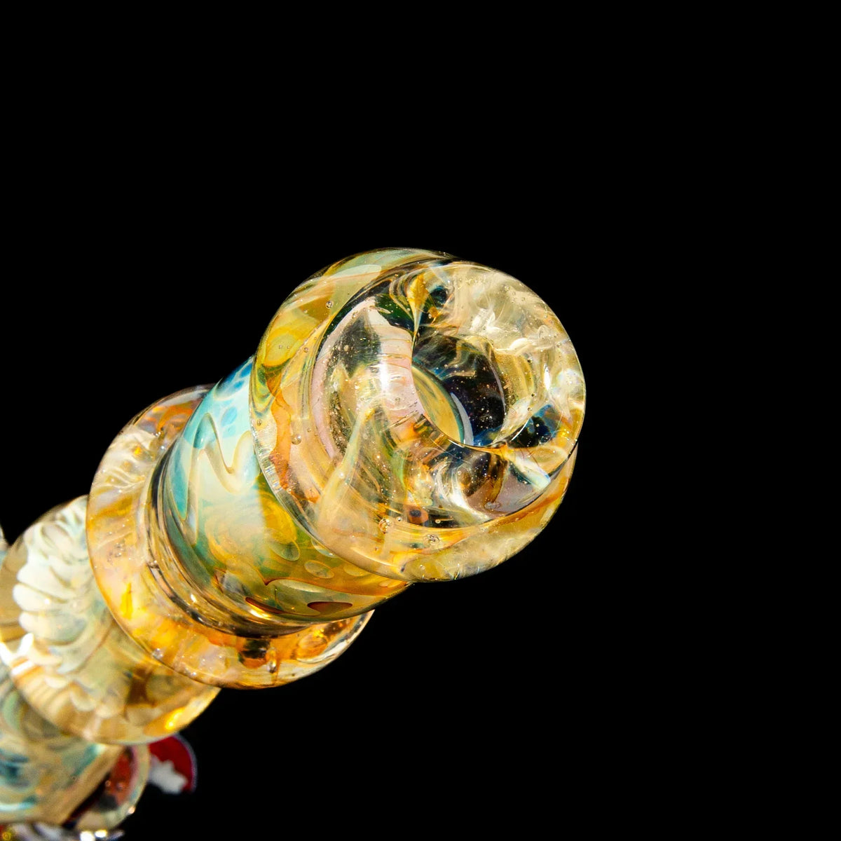 Close-up of colorful heady glass pipe mouthpiece with intricate patterns on black background