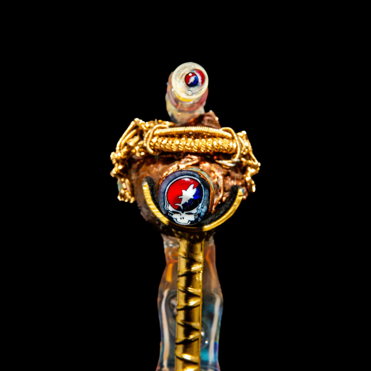 Heady glass pipe with gold wire accents and Grateful Dead skull design on black background