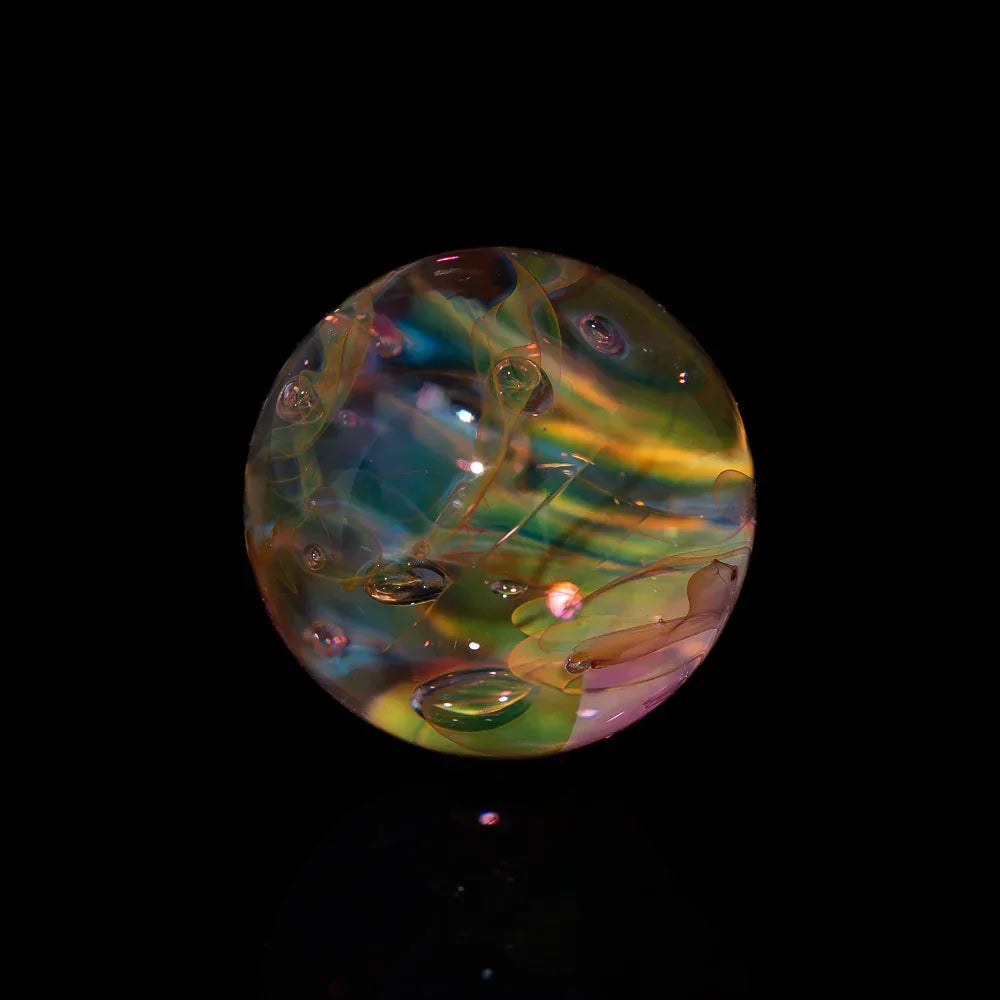 Colorful heady glass marble with swirling patterns and bubbles on black background