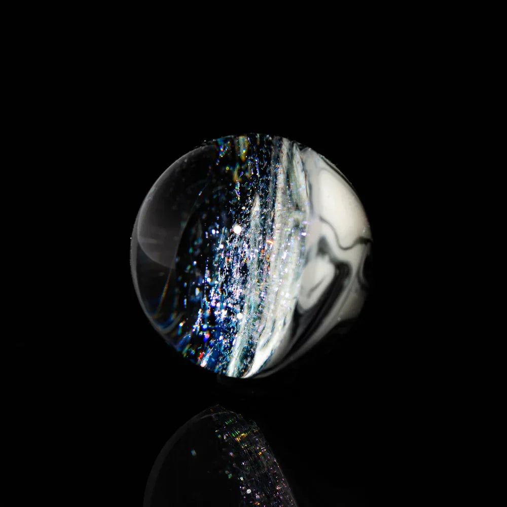 Handcrafted glass marble with galaxy swirl design and shimmering accents on black background