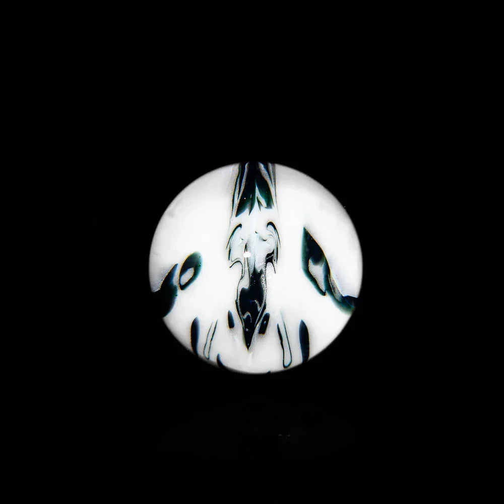 Handcrafted glass marble with abstract black and white pattern on a black background