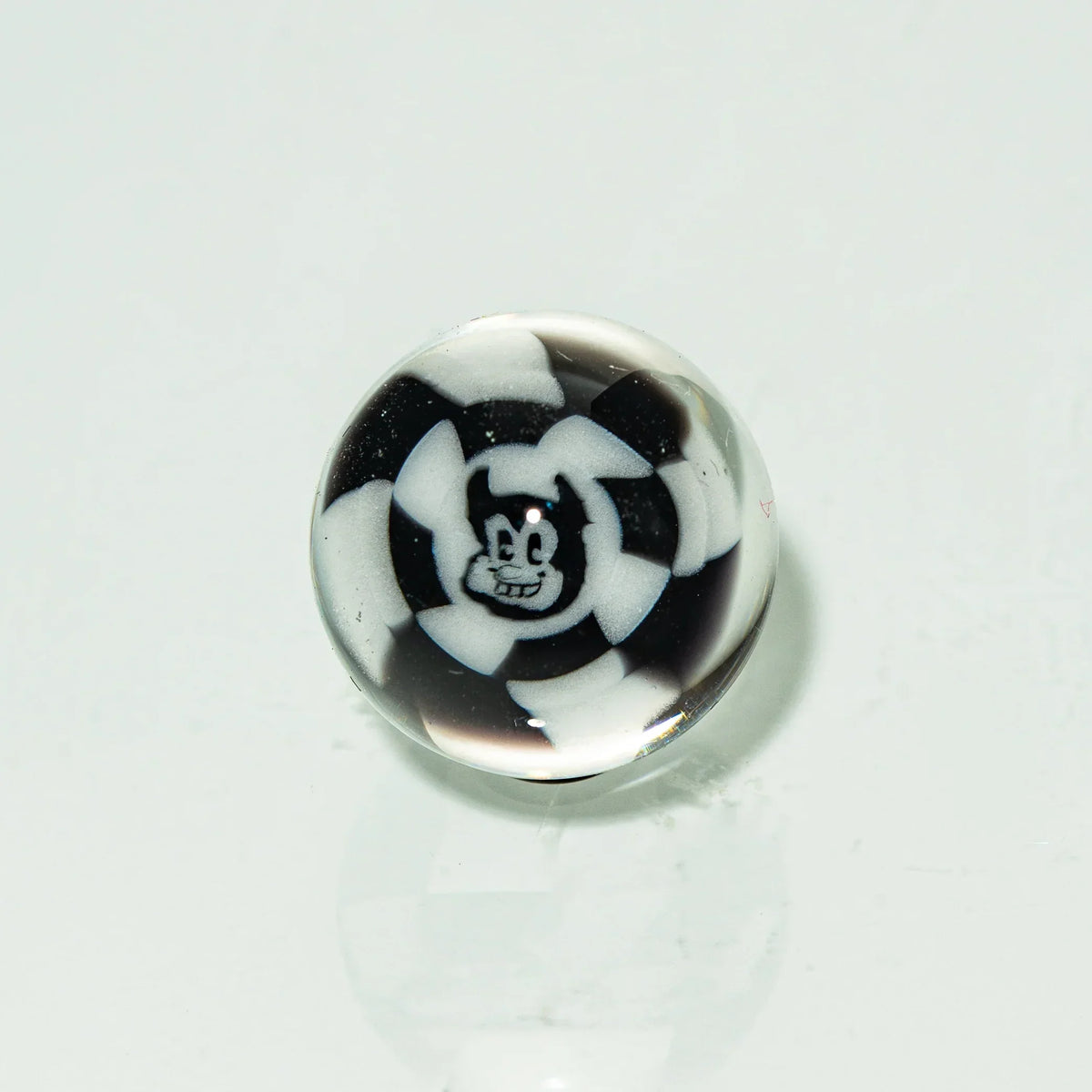 Black and white glass marble featuring a cartoon face design on a white background.
