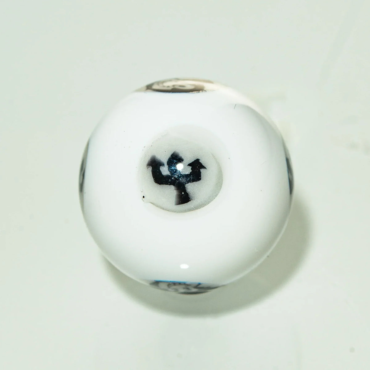 White glass marble with black arrow symbol, heady glass accessory on white background
