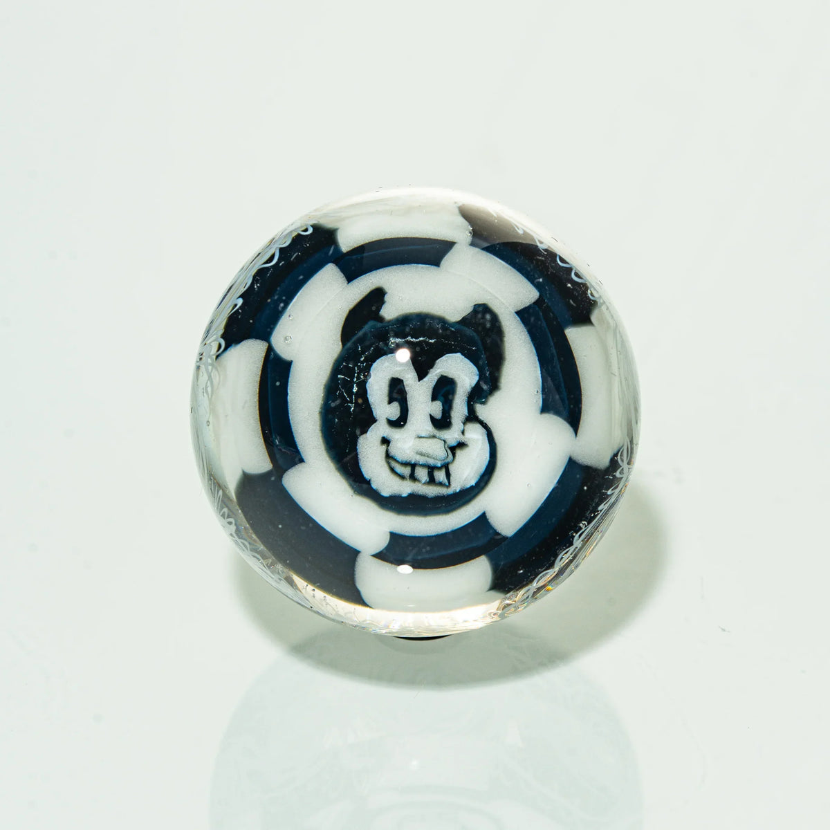 Handmade glass marble with black and white cartoon face and abstract pattern