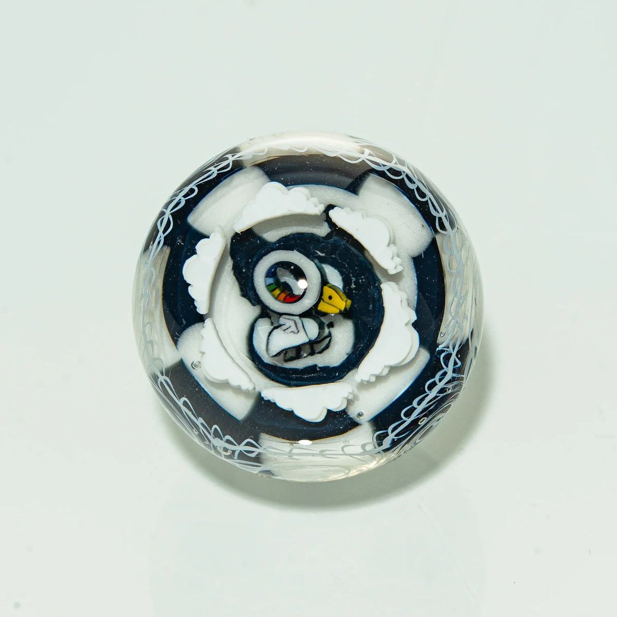 Art glass marble with penguin design and intricate white patterns on clear background