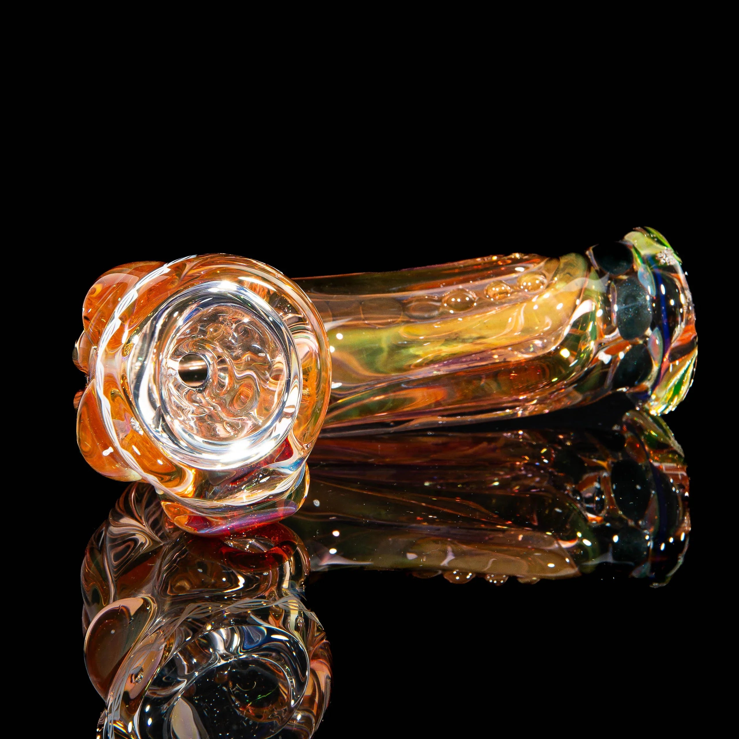 Colorful glass hand pipe with intricate patterns on a reflective black surface