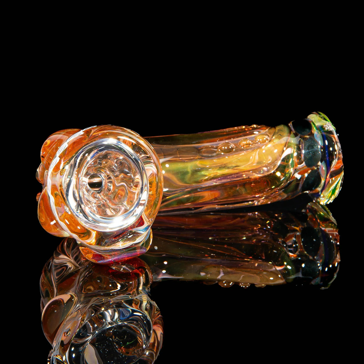 Colorful glass hand pipe with intricate patterns on a reflective black surface