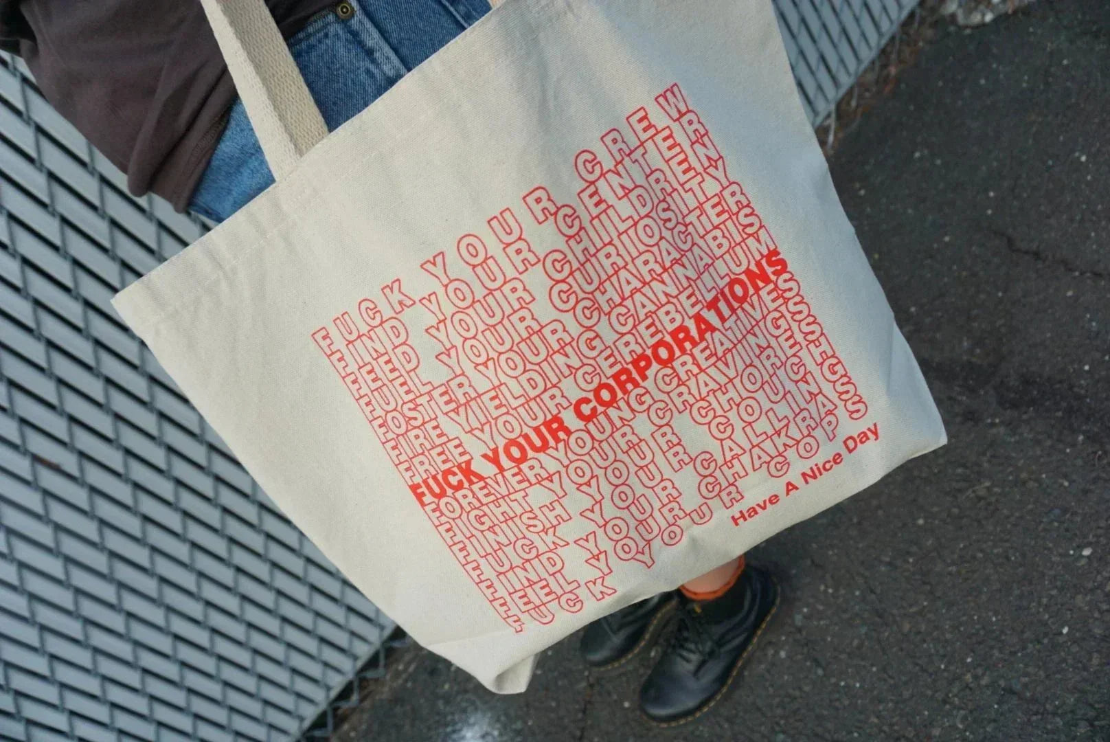 Canvas tote bag with bold red typography and patterns, person holding bag outdoors