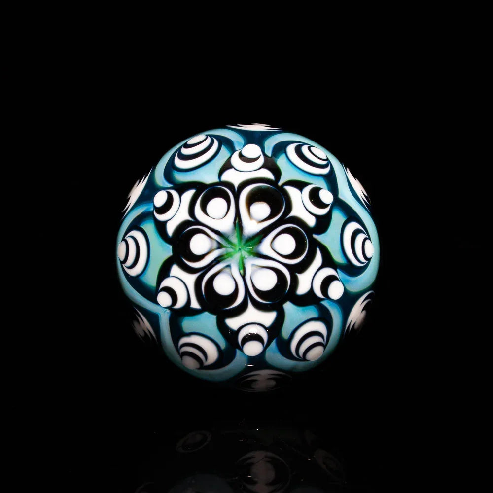 Intricate blue and white glass marble with hypnotic mandala pattern on black background