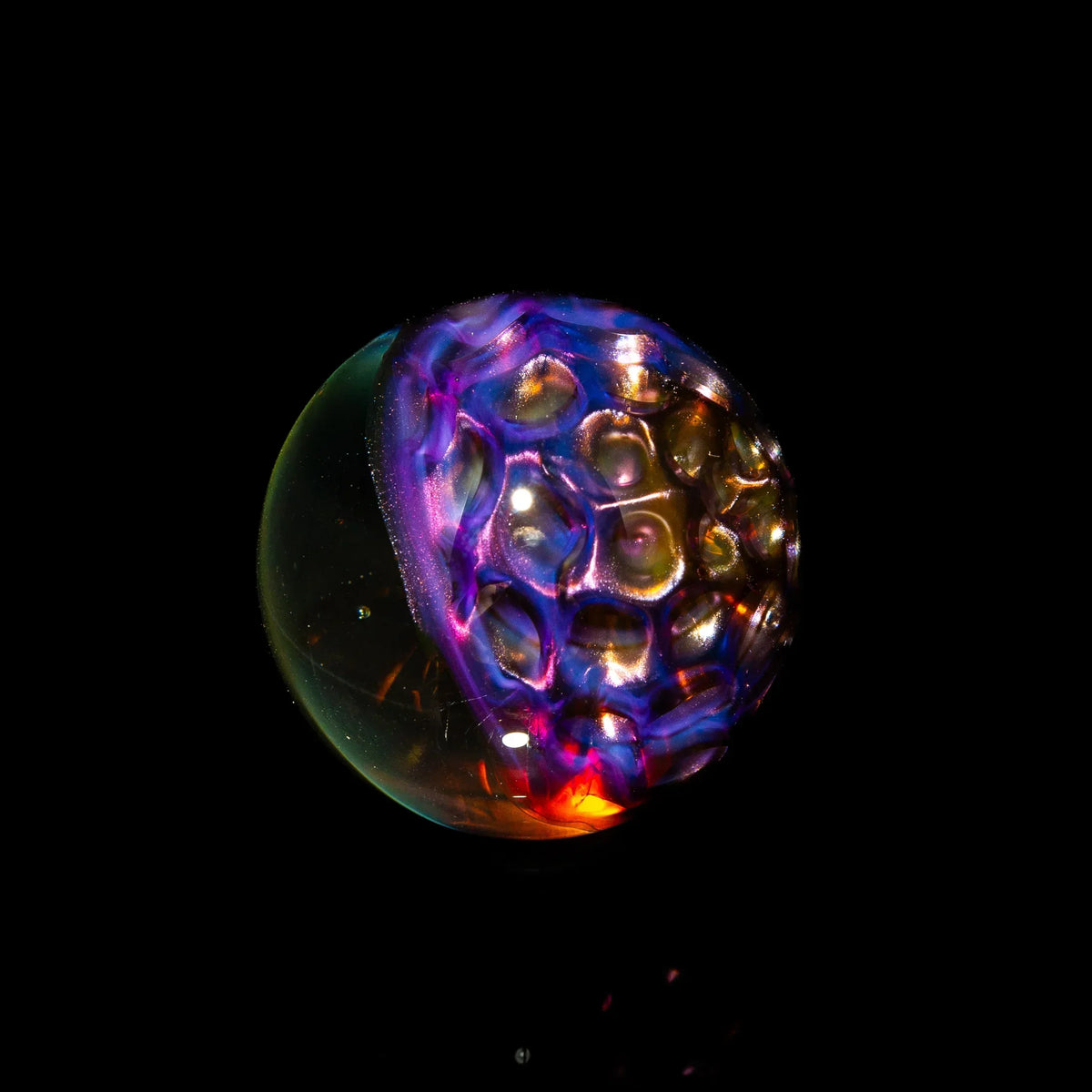 Colorful glass carb cap with honeycomb pattern, illuminated on black background