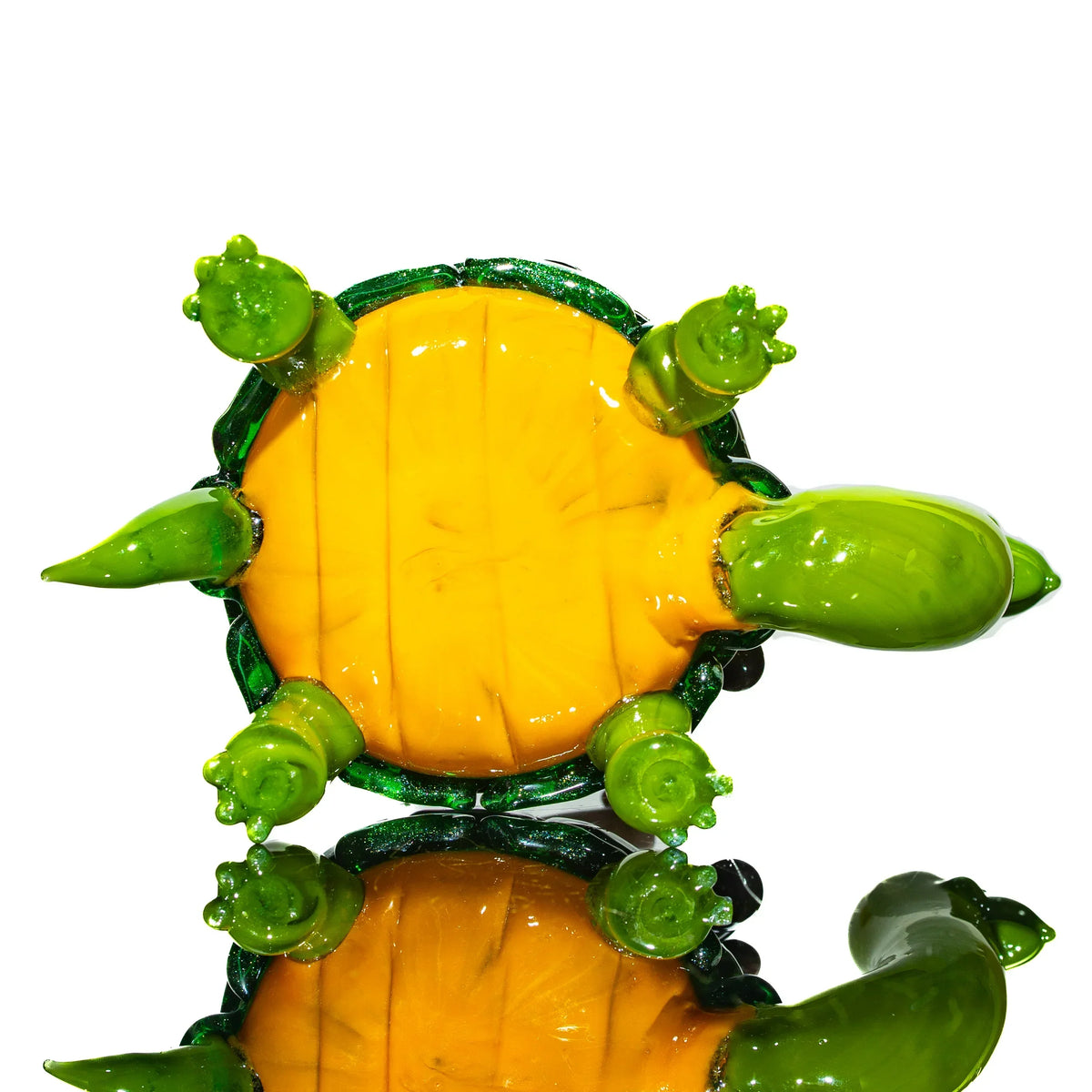 Handcrafted glass turtle art piece with vibrant yellow and green details, reflected on surface.