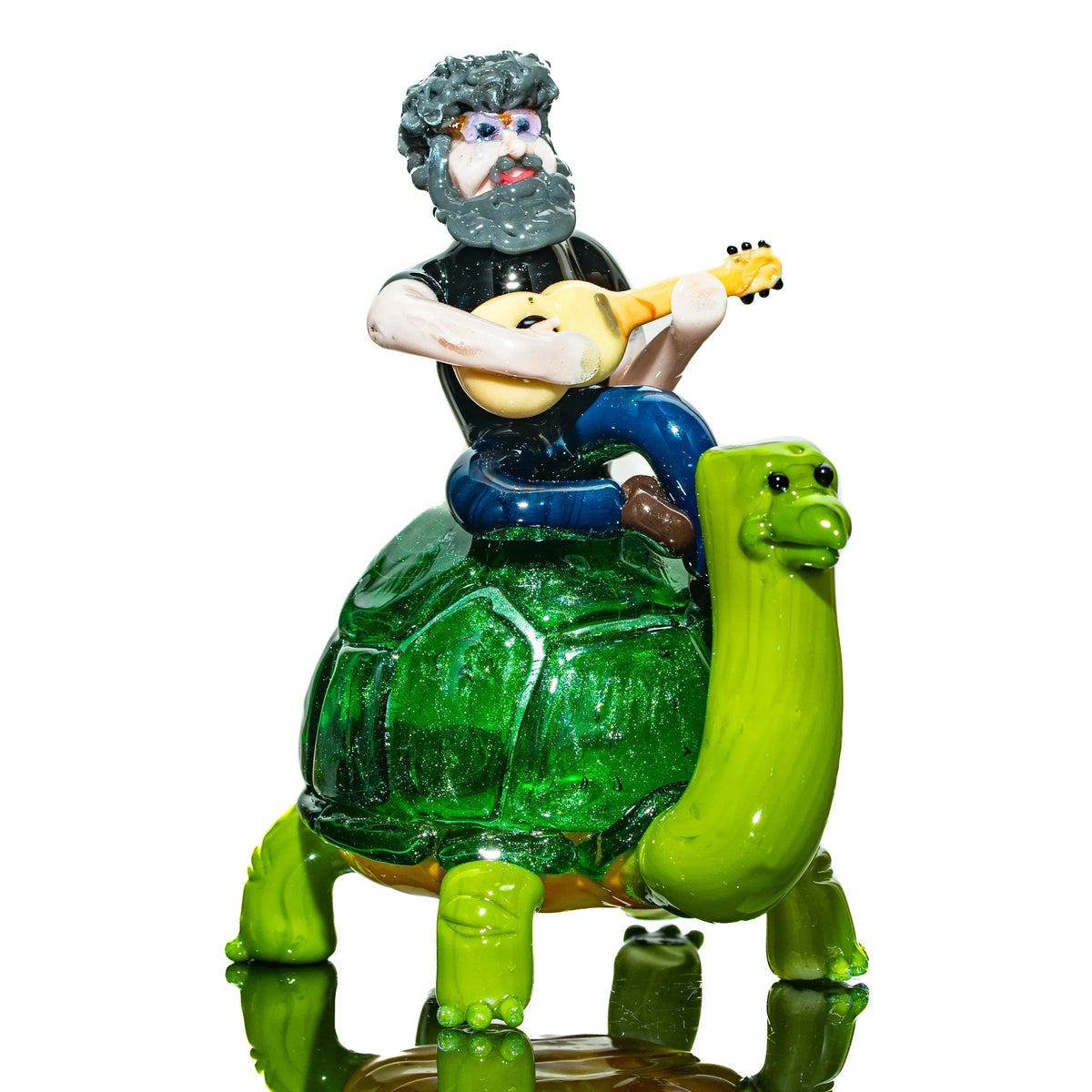 Handcrafted glass art of a bearded man playing guitar while riding a green turtle sculpture.