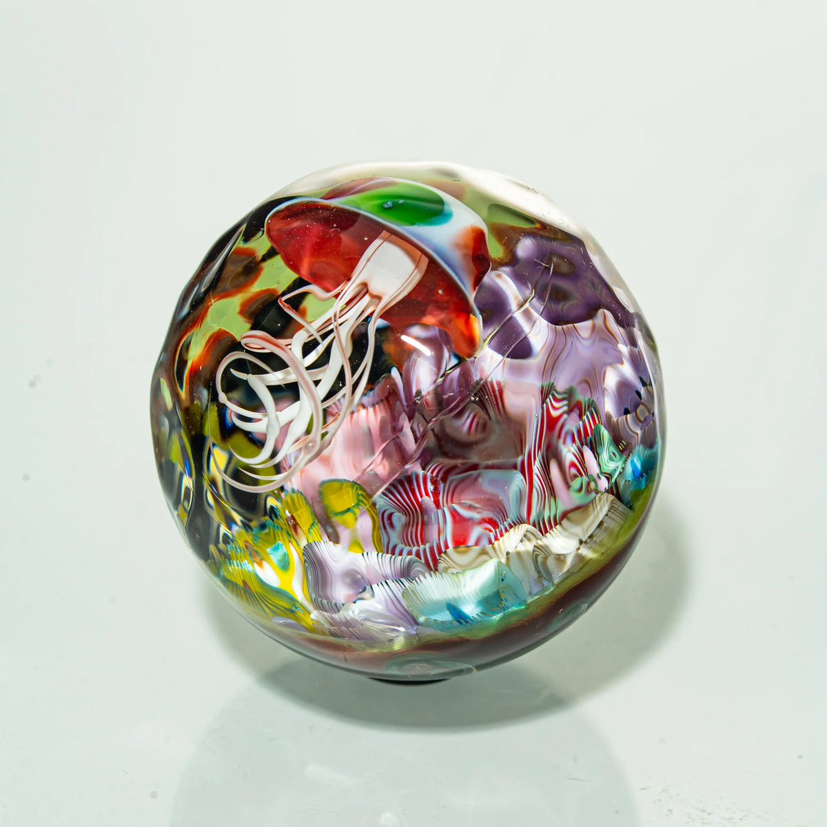 Hand-blown glass marble with colorful jellyfish design and intricate patterns