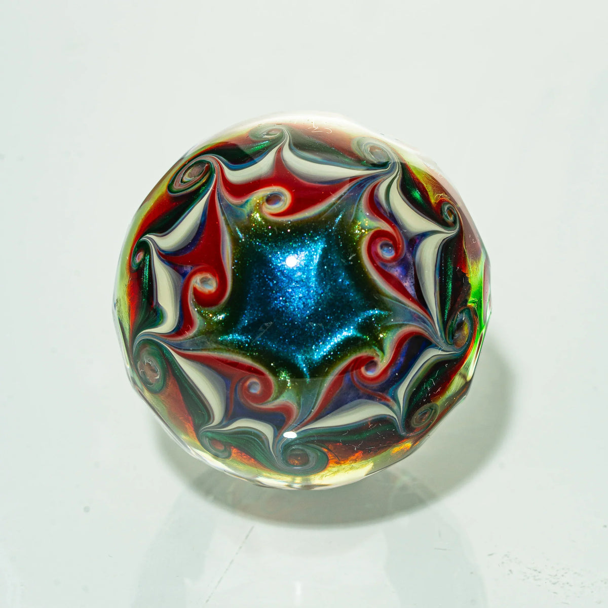 Heady glass marble with intricate swirling red, blue, green, and white patterns