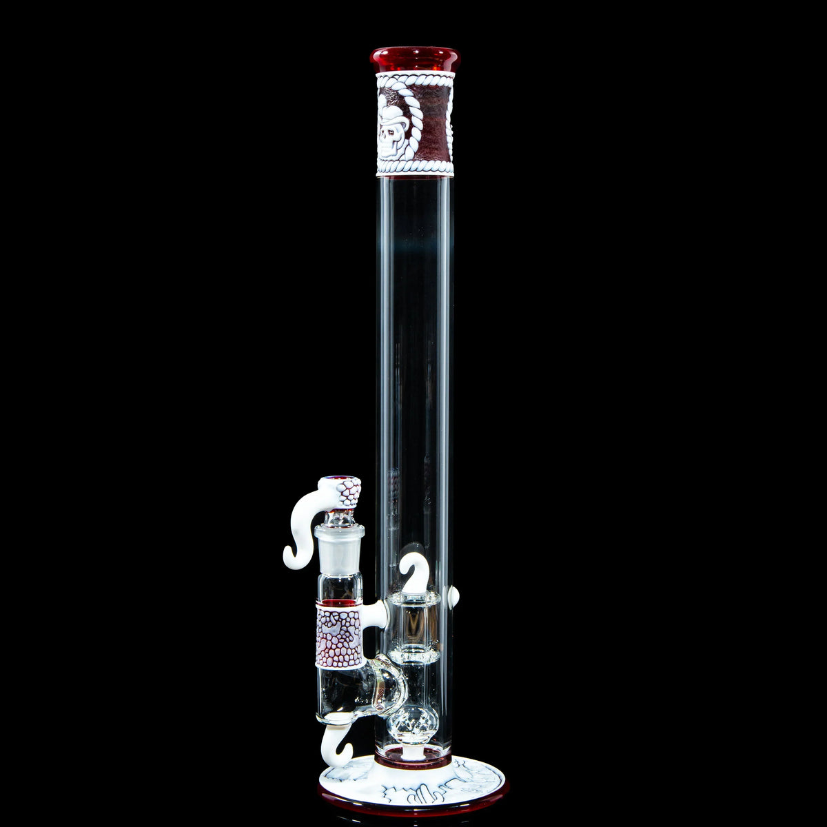 Heady glass bong with red and white accents, artistic details, and clear chamber on black background