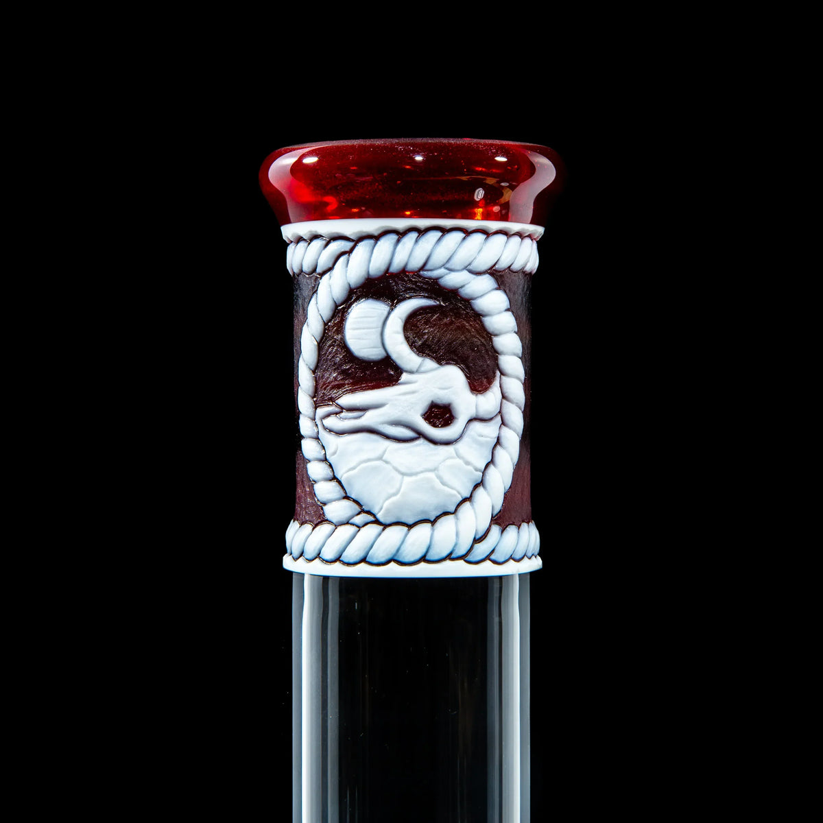 Close-up of a custom glass bong with a red rim and white decorative moon and animal design