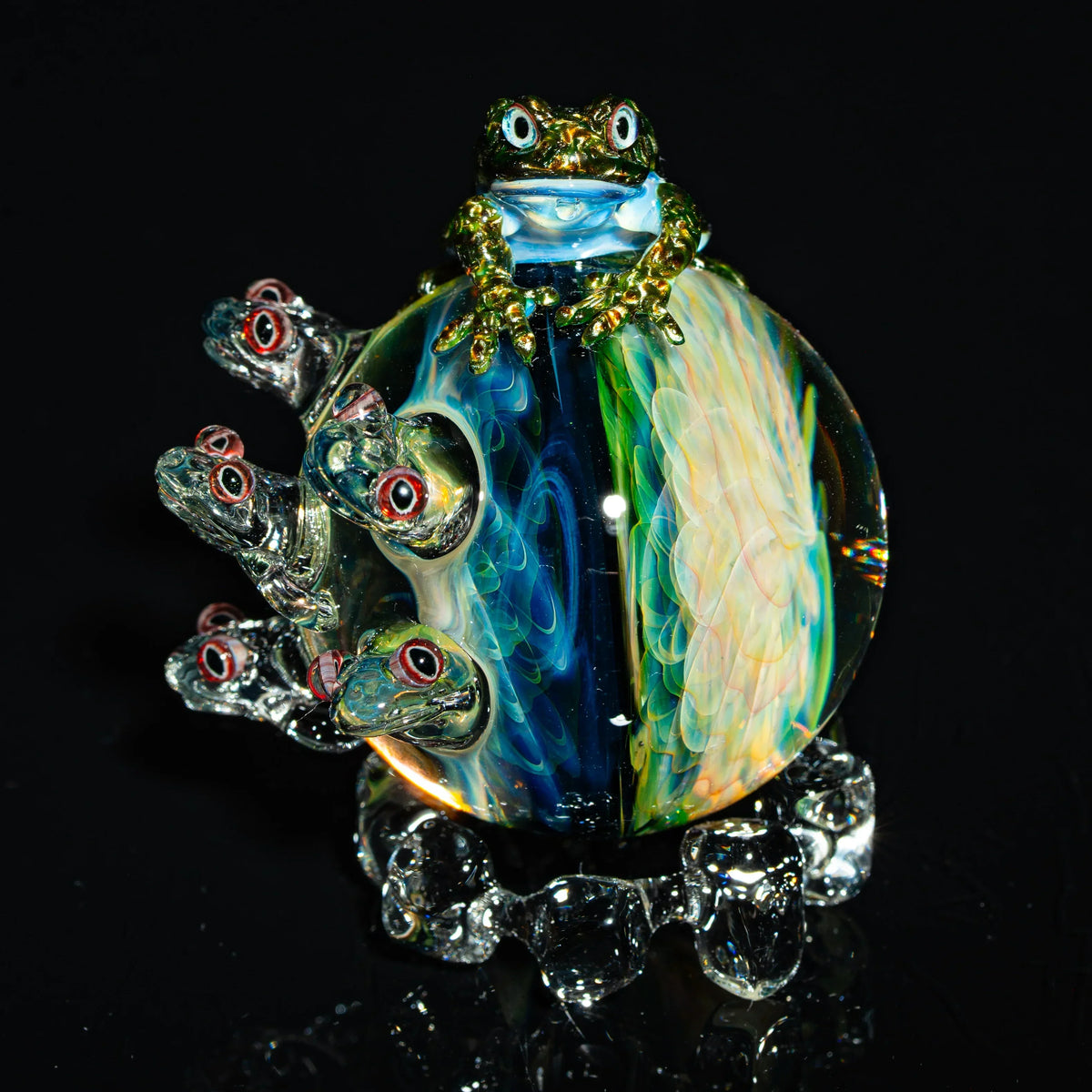 Colorful heady glass art marble with detailed frog and eye accents on black background