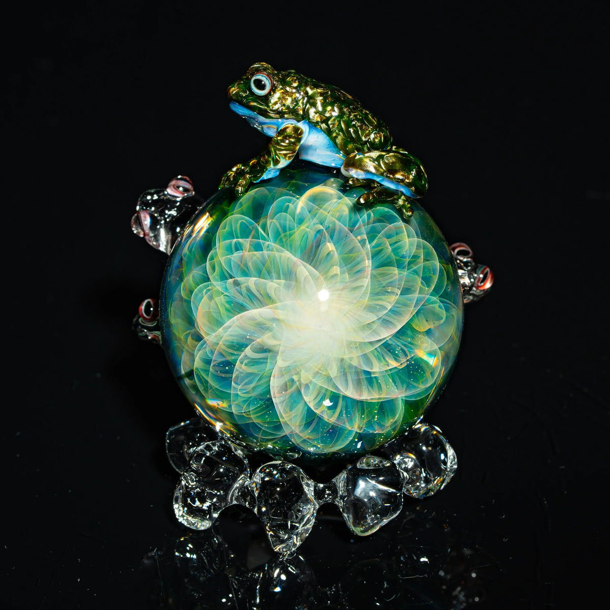 Handcrafted glass art sphere with intricate flower pattern and realistic frog sculpture on top