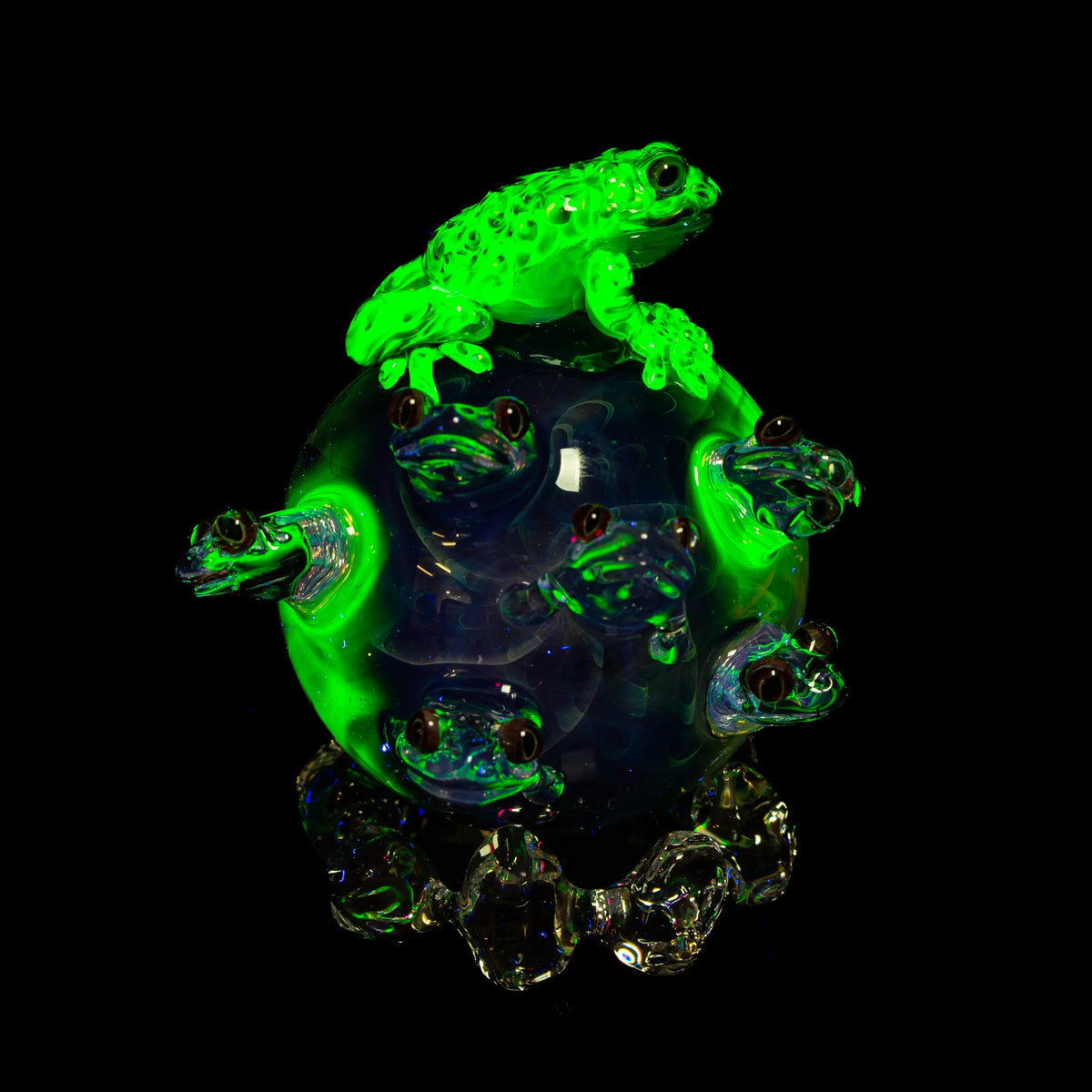 Glowing glass art orb with multiple frog sculptures and neon green highlights