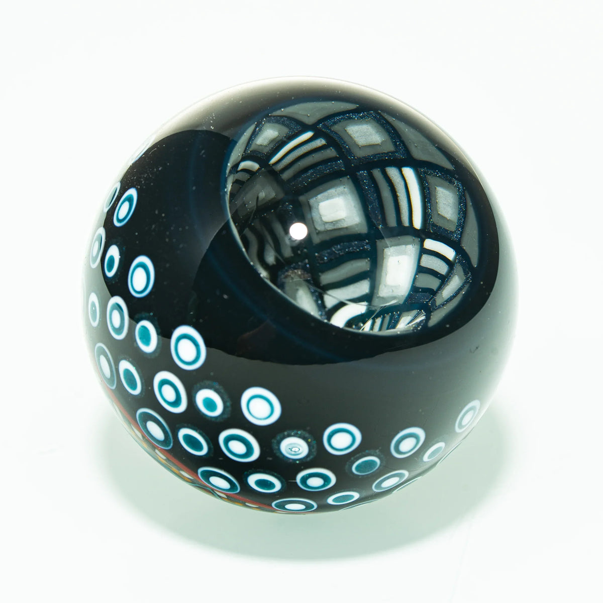 Hand-blown glass marble with blue dot pattern and intricate geometric design
