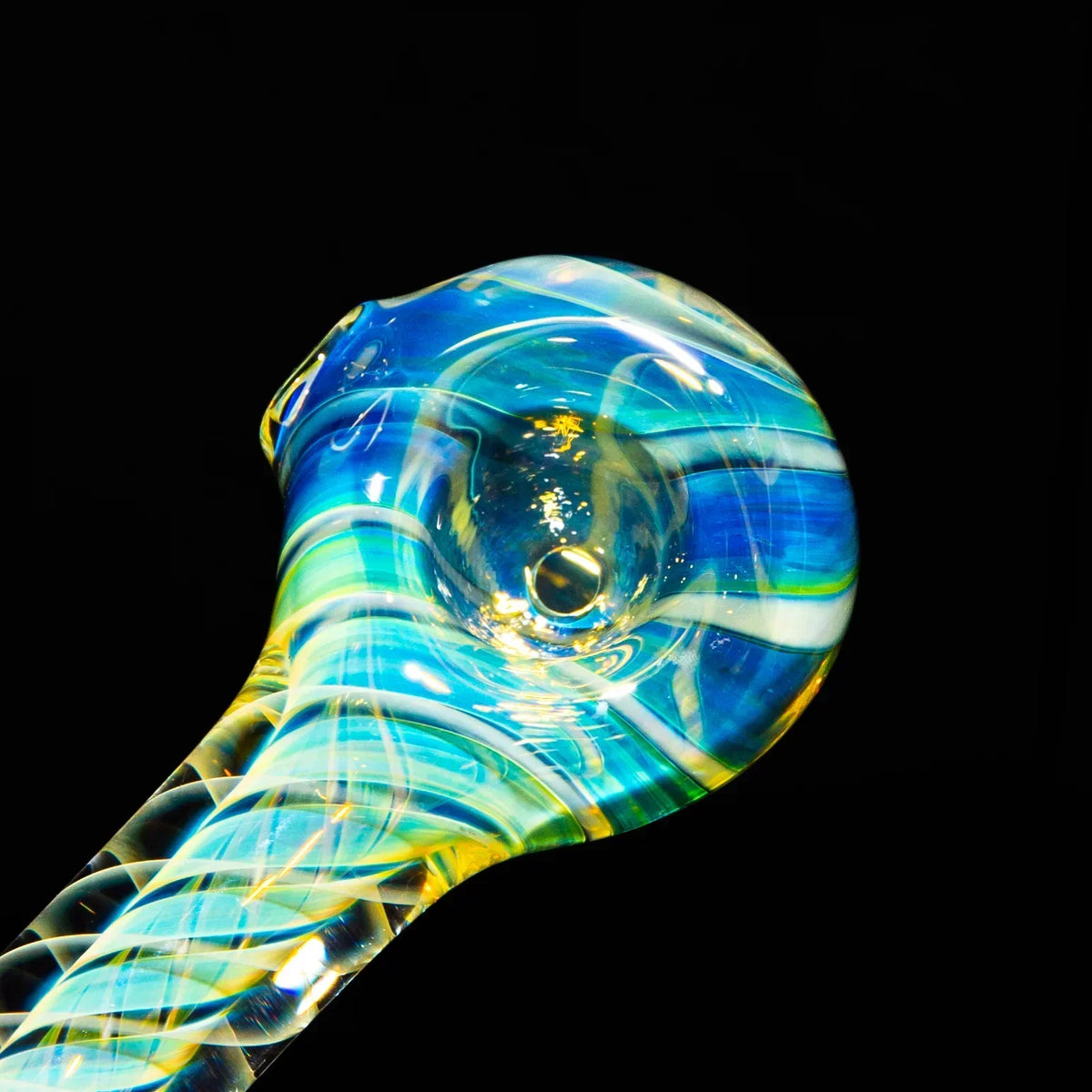 Close-up of a colorful hand-blown glass pipe with blue, green, and yellow swirls