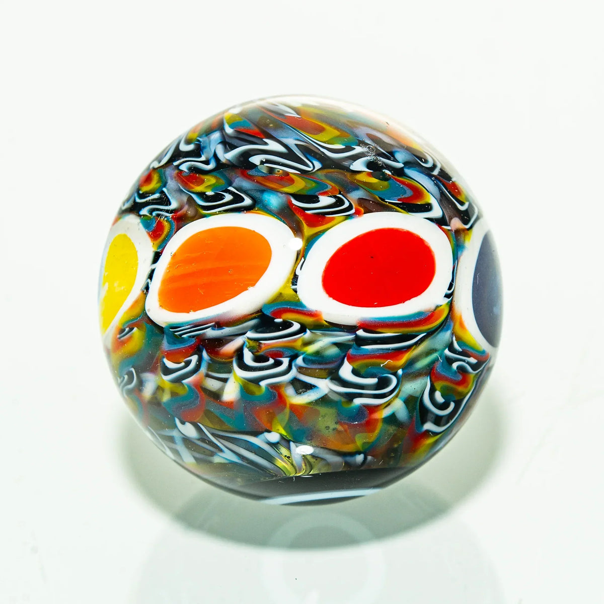 Colorful glass marble with vibrant swirls and dot design on a white background