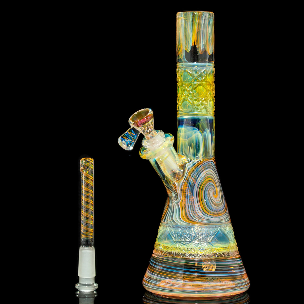 Colorful glass beaker tube with intricate patterns and matching downstem against a black background.