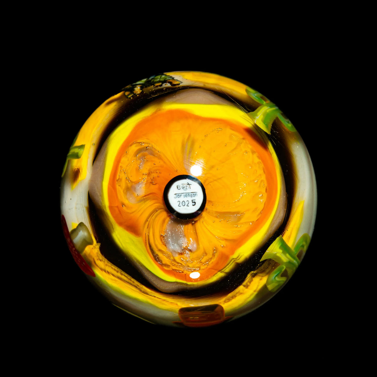 Handblown glass art sphere with vibrant yellow and orange swirls, black background