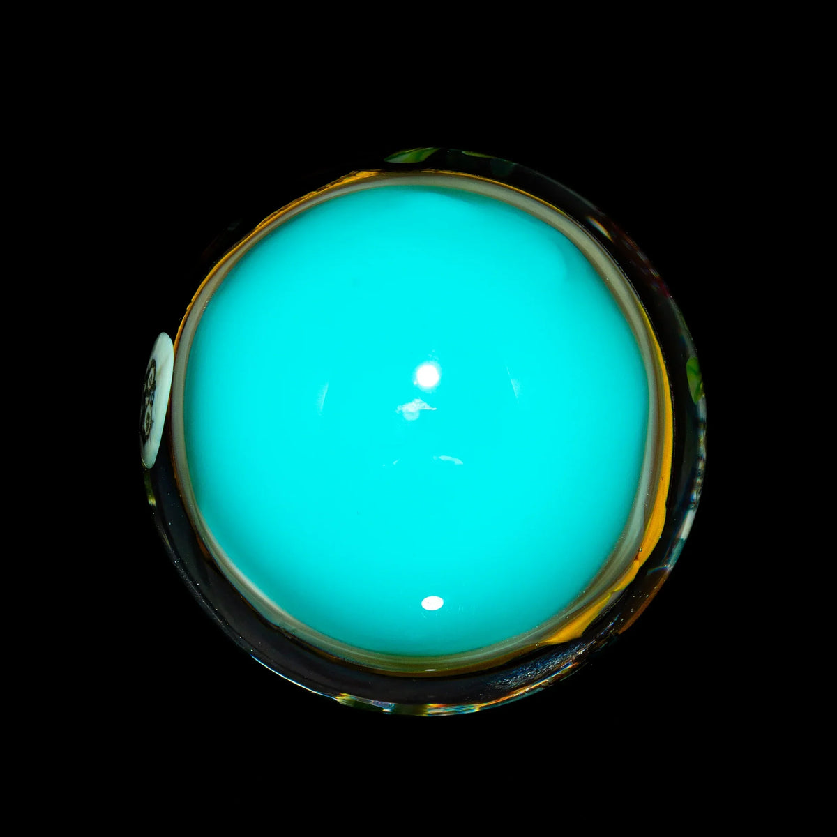 Bright blue glass marble or carb cap with a glossy finish on a black background
