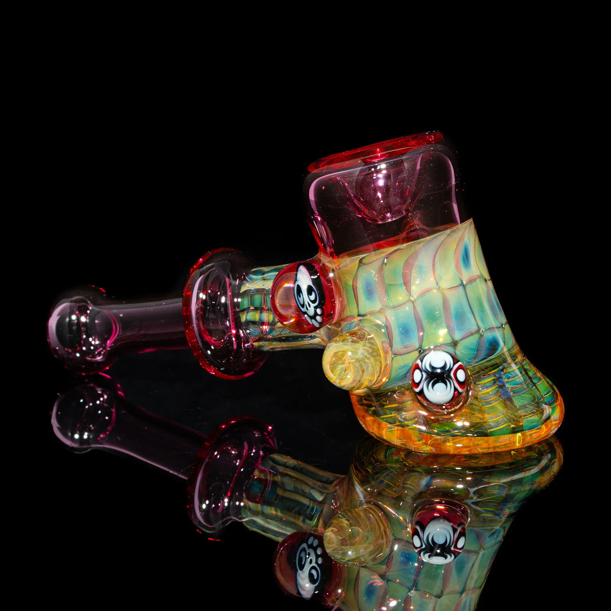 Colorful heady glass pipe with skull details and iridescent textures on a black background