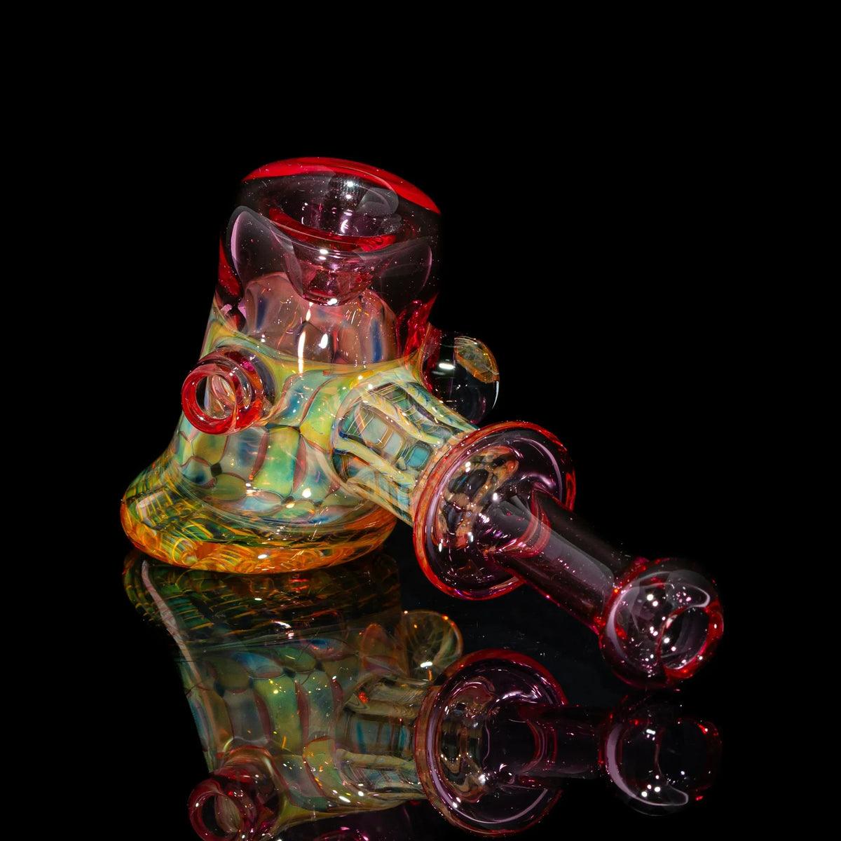 Colorful heady glass water pipe with vibrant red, yellow, and green accents on black background