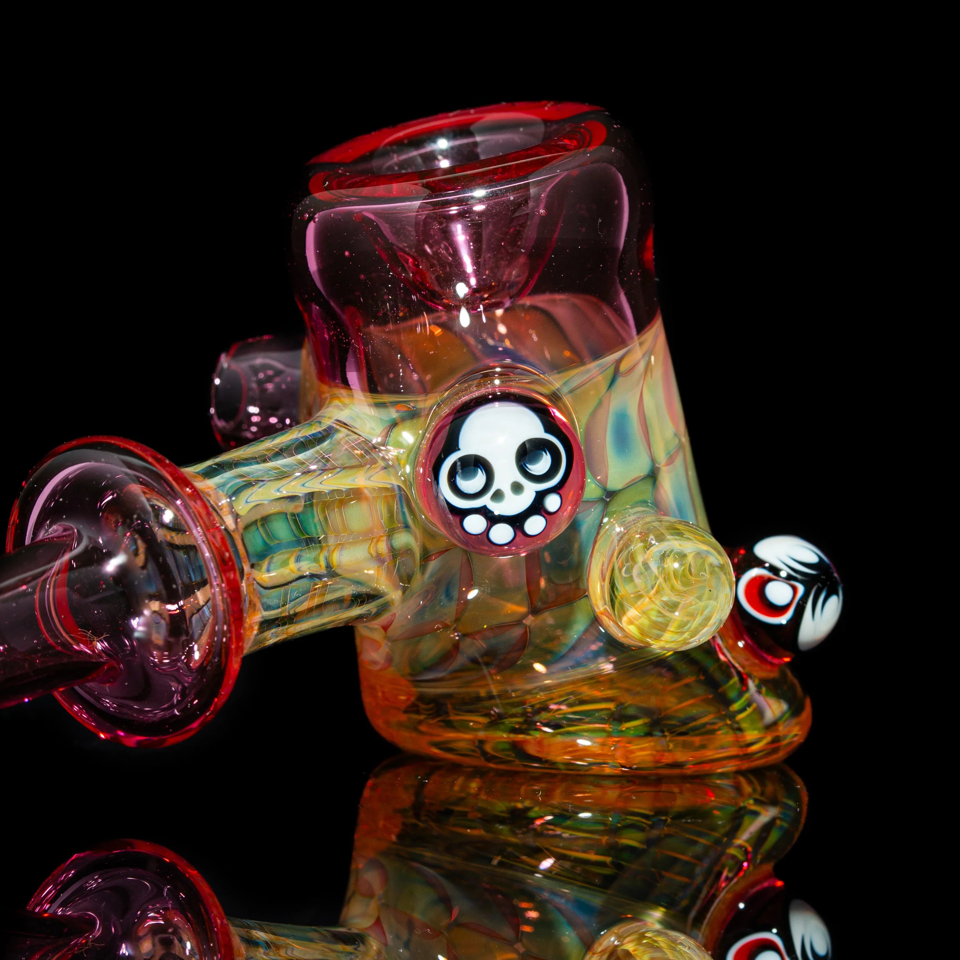 Colorful heady glass water pipe with skull accents on a black background