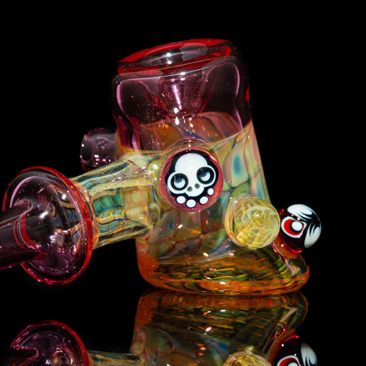Colorful heady glass water pipe with skull accents on a black background