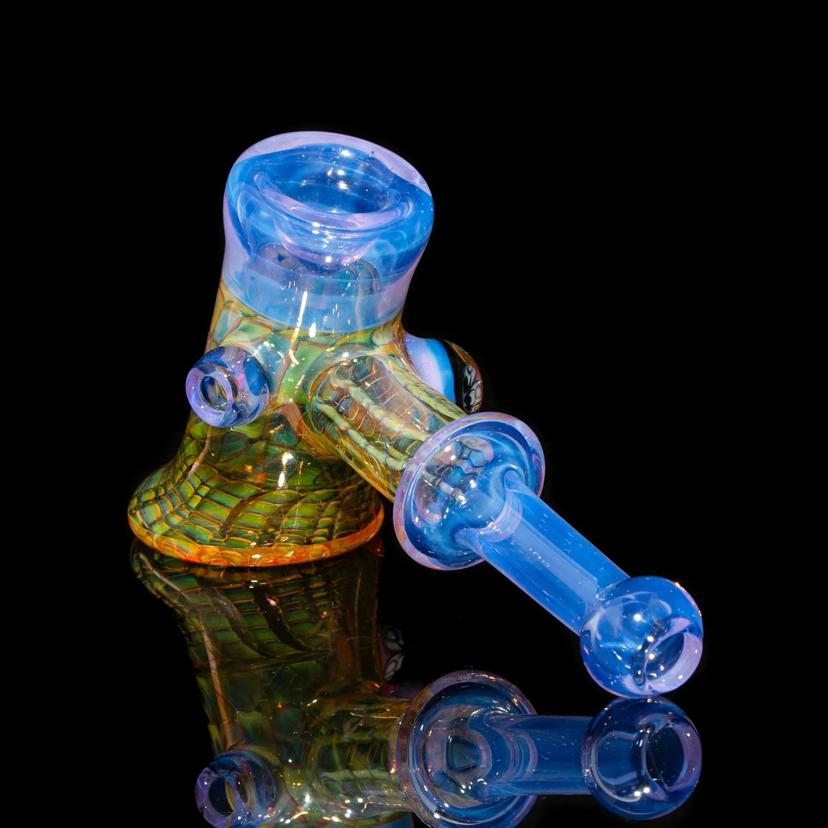 Colorful heady glass hand pipe with blue and yellow accents on black reflective background