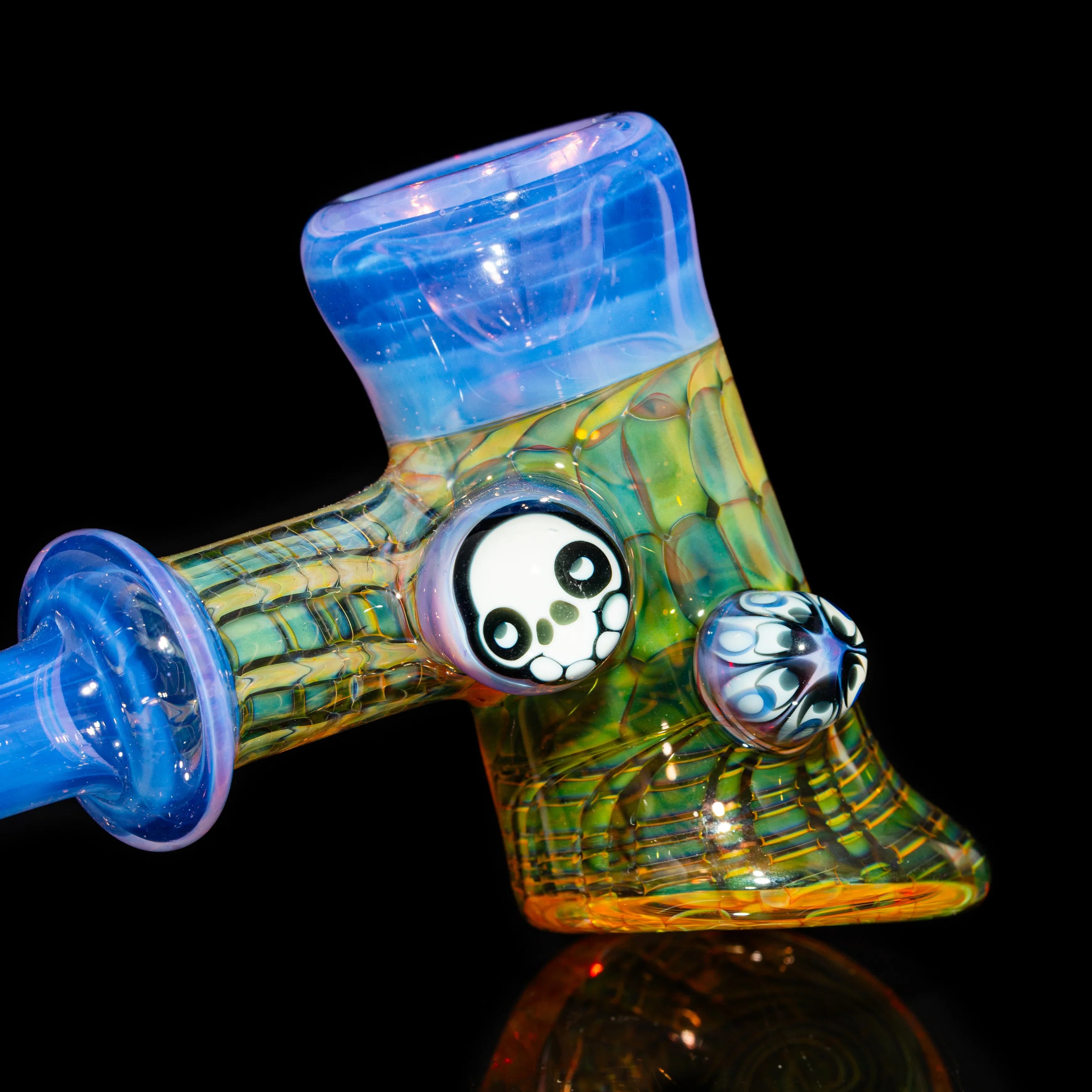 Colorful heady glass pipe with skull accent and intricate patterns on black background