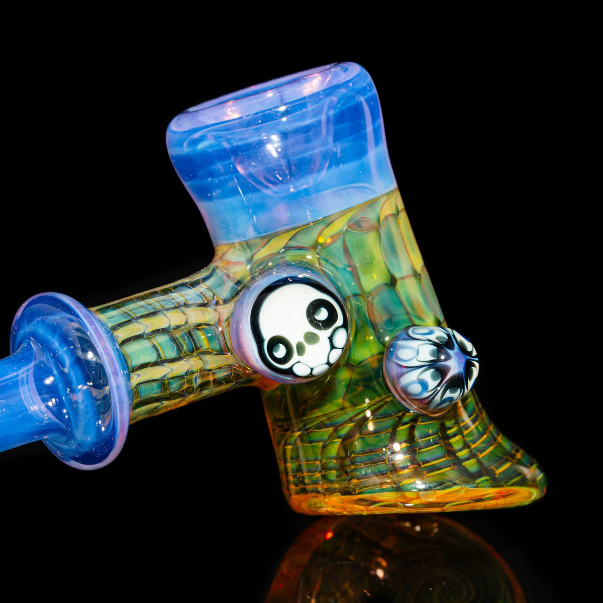 Colorful heady glass pipe with skull accent and intricate patterns on black background