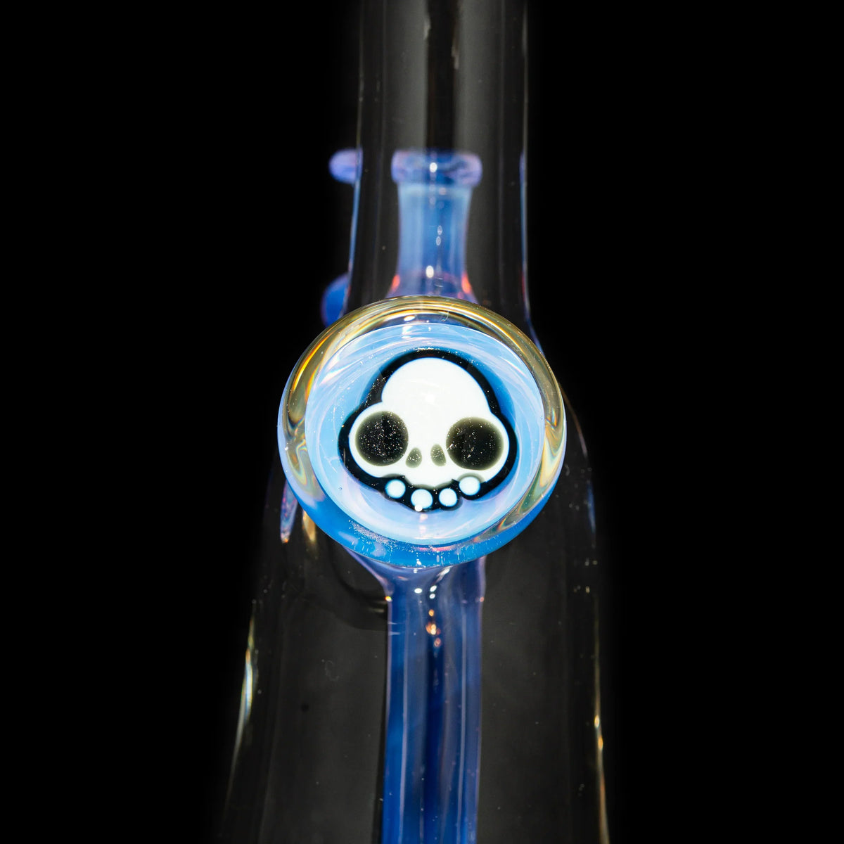 Close-up of glass pipe with skull detail, heady glass accessory on black background