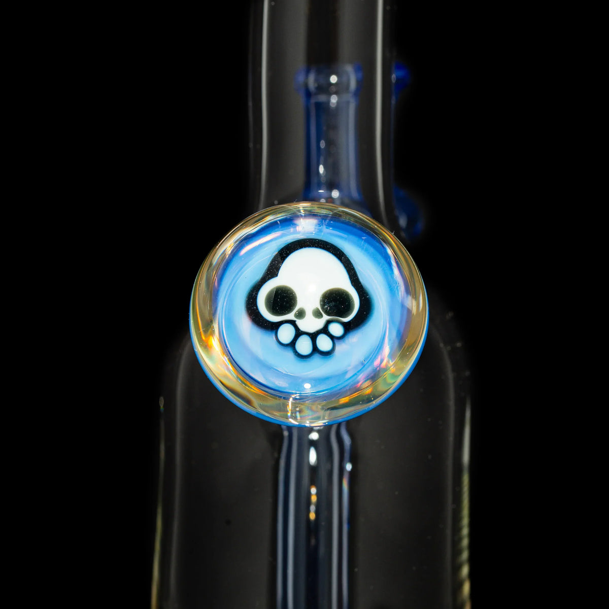 Close-up of glass water pipe with blue accent and skull design medallion