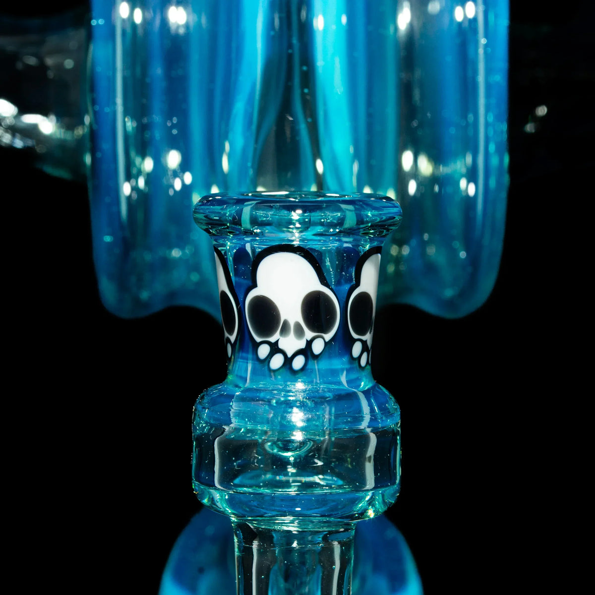 Close-up of blue glass water pipe with decorative skull accents, heady glass detail