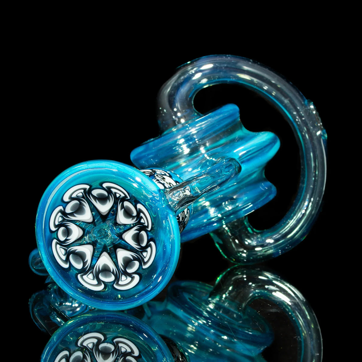 Blue heady glass carb cap with intricate black and white heart pattern, displayed on black background